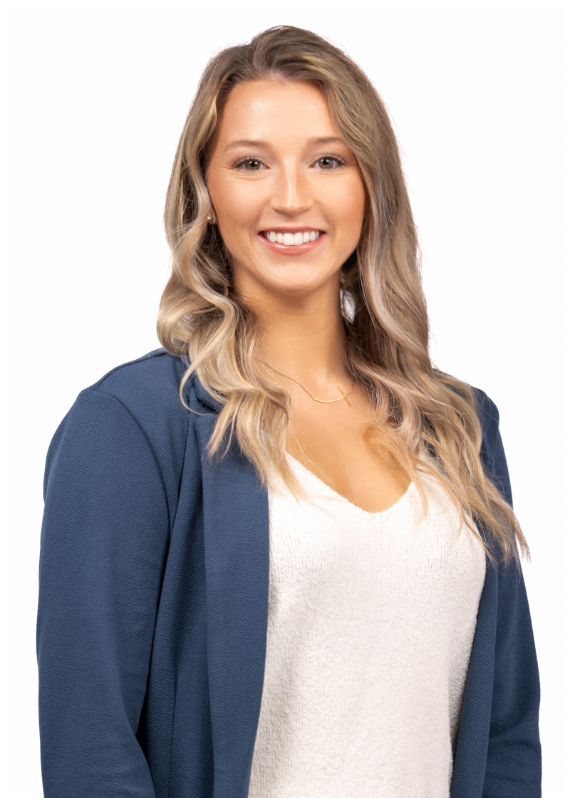 A woman with long blond hair wearing a white shirt and blue long sleave sweater.